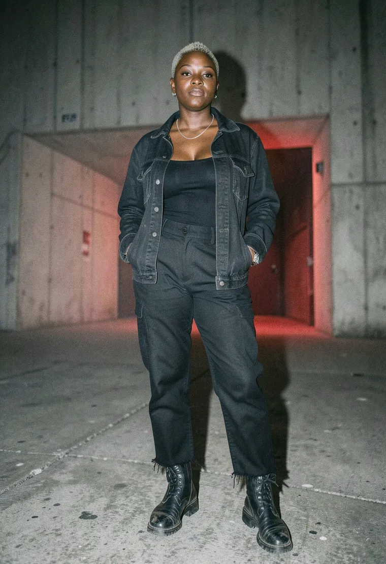 36-year-old Black British sound artist, soft butch energy, cropped fade with bleached tips, standing like she already has a cigarette behind her ear even though she doesn't smoke