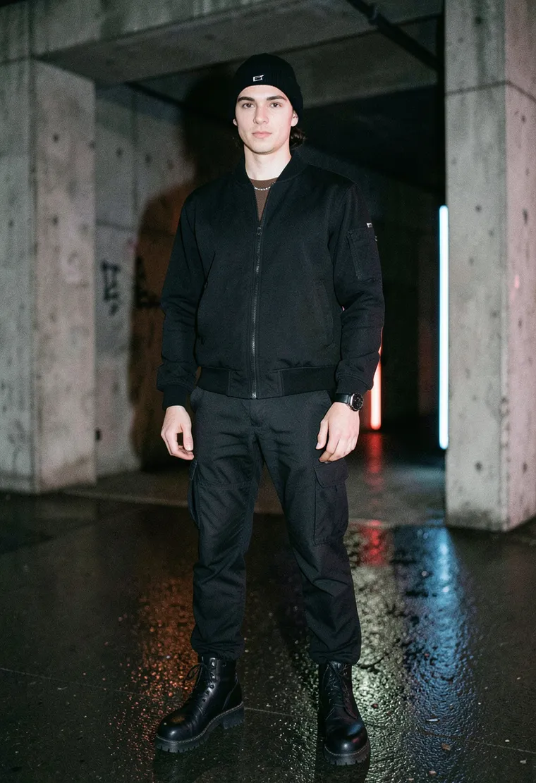 28-year-old non-binary person of mixed German‑Polish heritage, slim build, low‑key confidence, long dark hair pulled into a low bun, immersed in the underground techno scene
